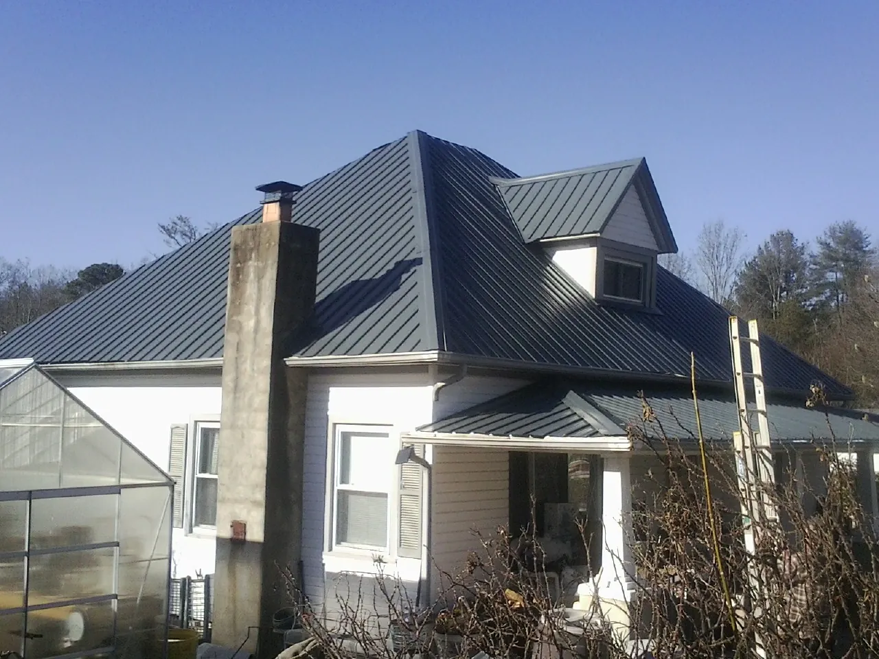 Dark blue standing seam metal roof on a white farmhouse with dormer — Slate & Tile Roof Repair by Roofing Brothers in Ford City