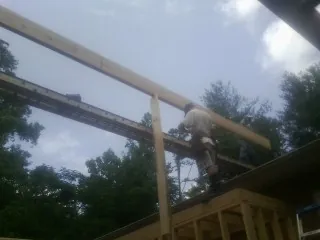Carpenter setting a ridge beam over a new addition frame — Ice Dam Removal by Roofing Brothers in Ford City