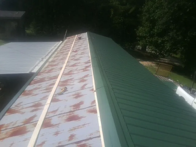 Old rusted panels beside newly installed green metal roofing — Wind Damage Roof Repair by Roofing Brothers in Ford City