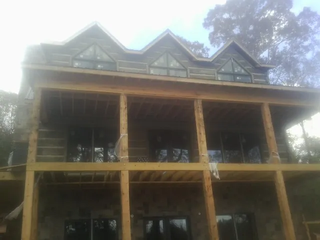 Dormers and porch framing on a large log home under construction — Roof Coating work by our crew in Ford City