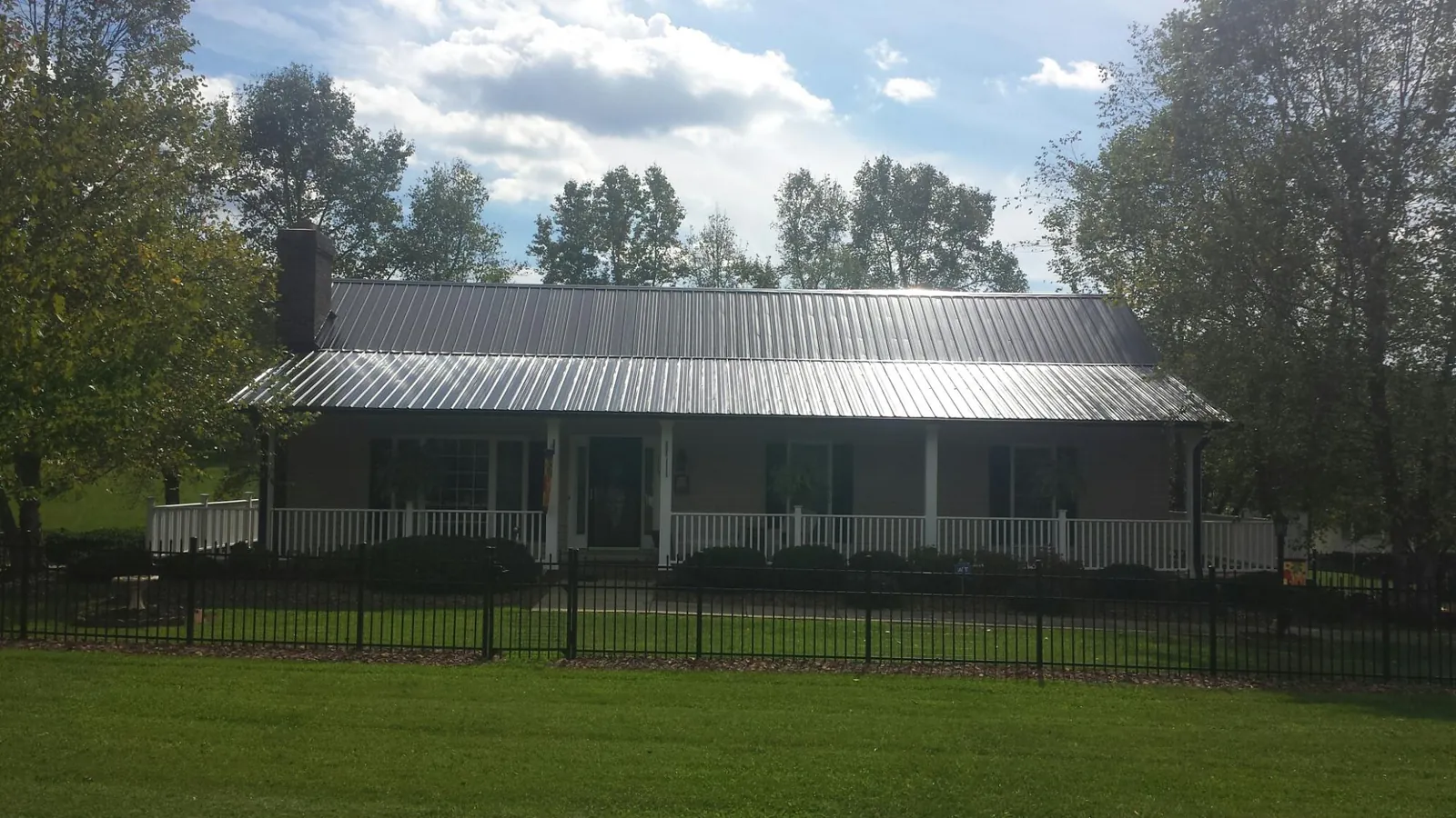 Gray metal roof on a brick ranch with a full width front porch — Gutter Guard Installation work by our crew in Ford City