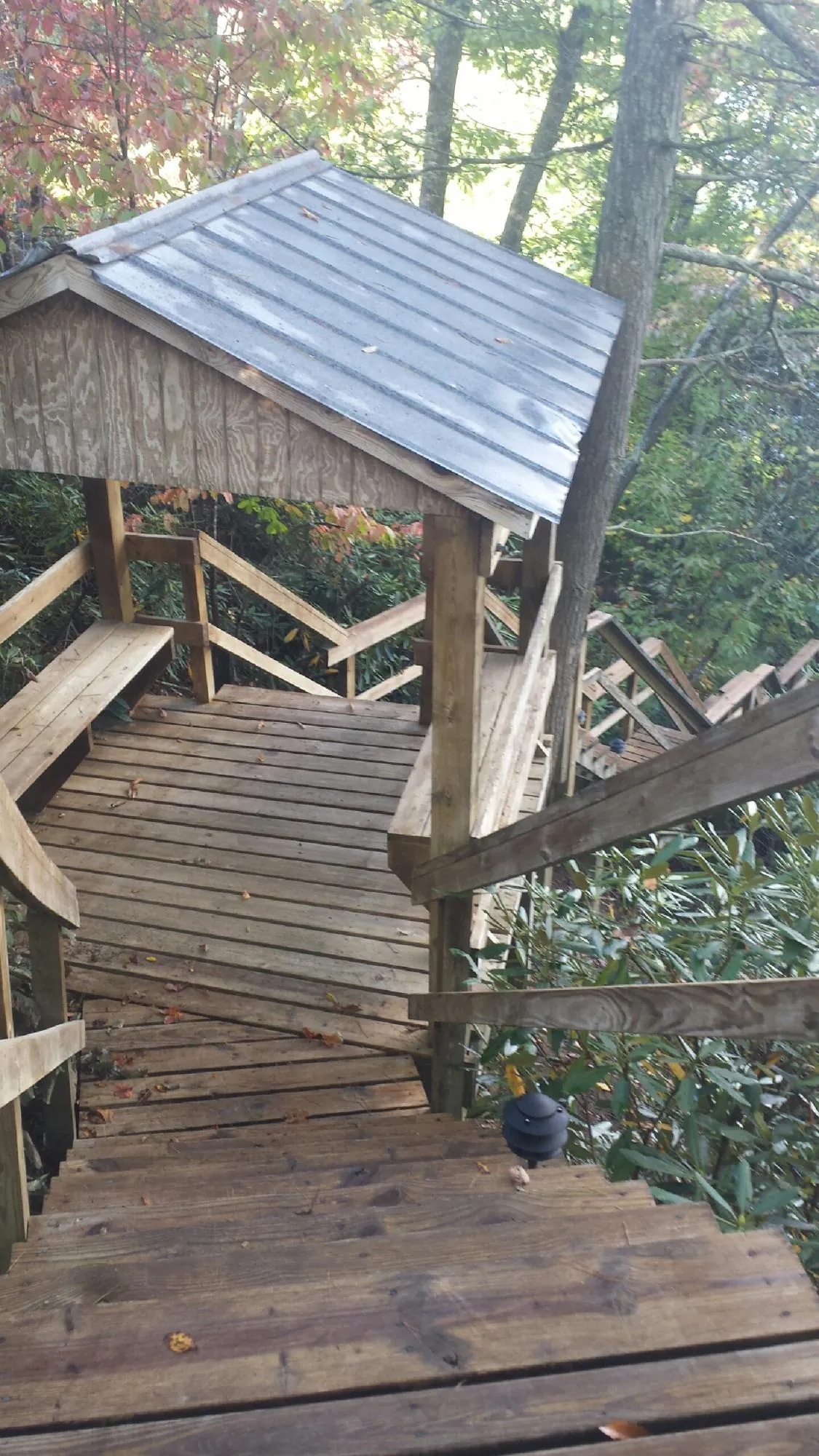 Metal roofed shelter over wooden steps on a wooded walkway — Skylight Repair & Installation work by our crew in Ford City