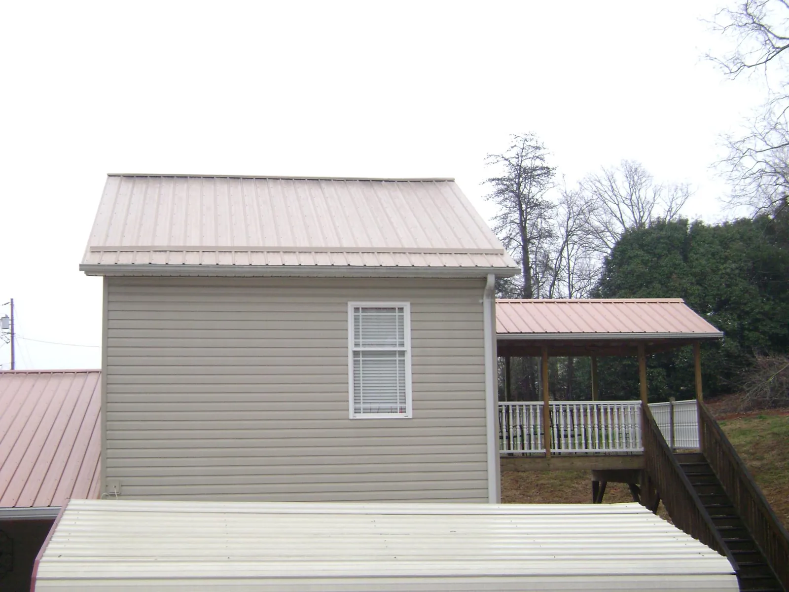Tan metal roofs on a two story addition and attached porch, from a Roof Replacement job in Ford City