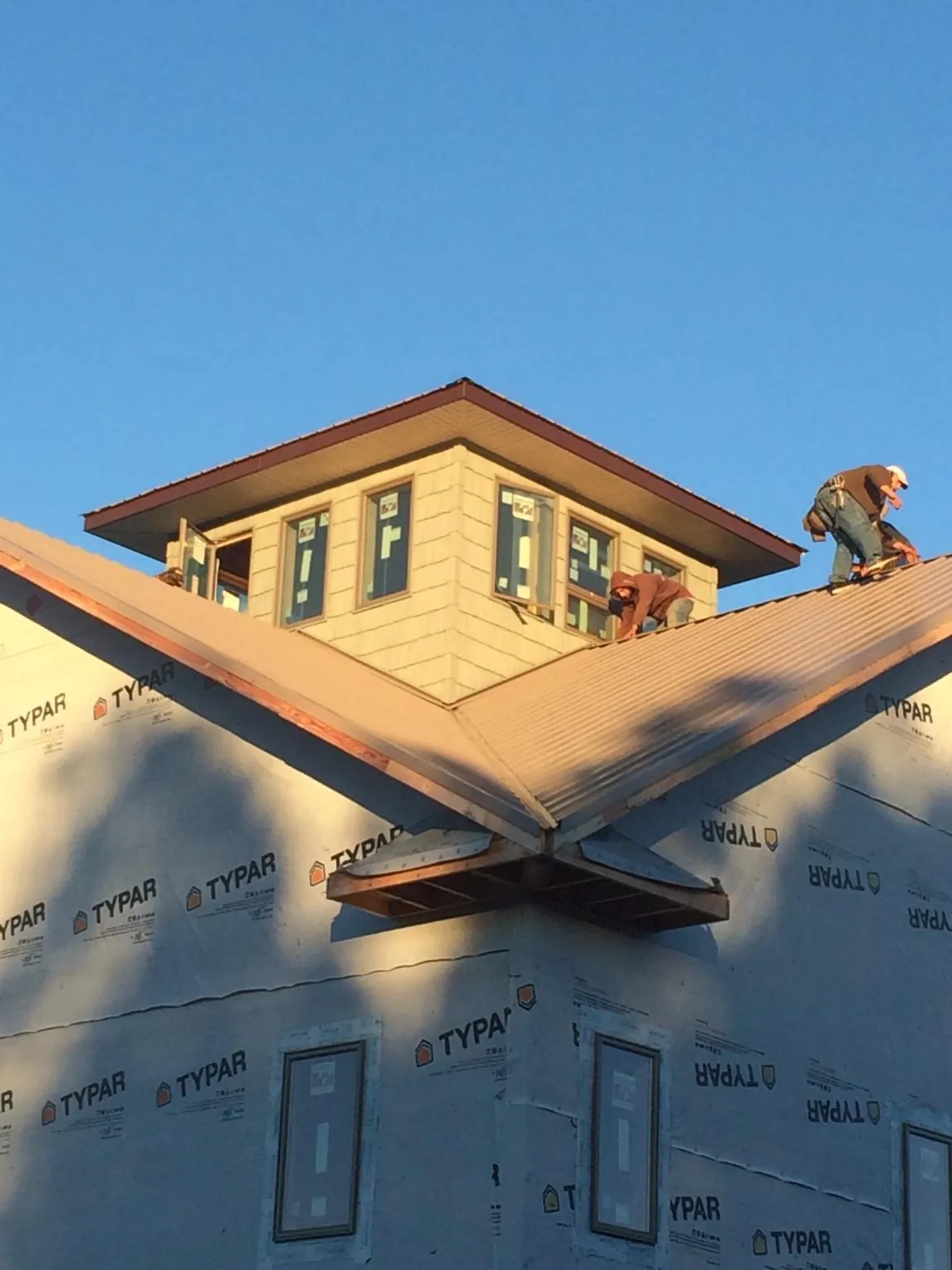 Roofers working around a rooftop cupola on a new metal roof at sunset — Roof Waterproofing in Ford City by Roofing Brothers